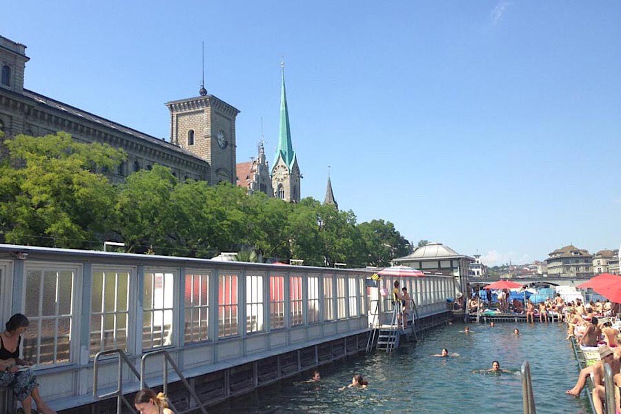 Flussbadi in Zürich mit Bäumen und Turm in Hintergrund