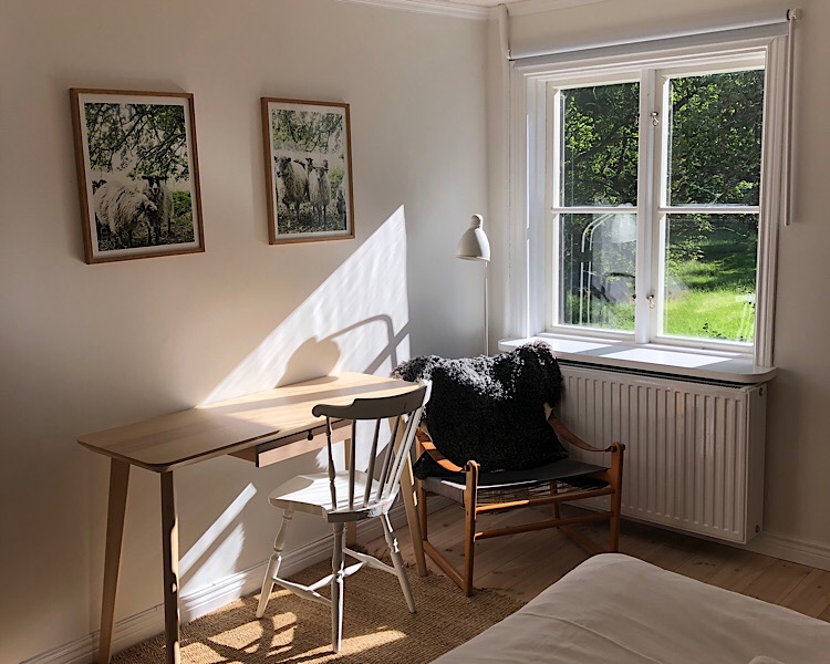 Schreibtisch mit weissem Stuhl, Ausblick in den Garten und 2 Schafbilder 