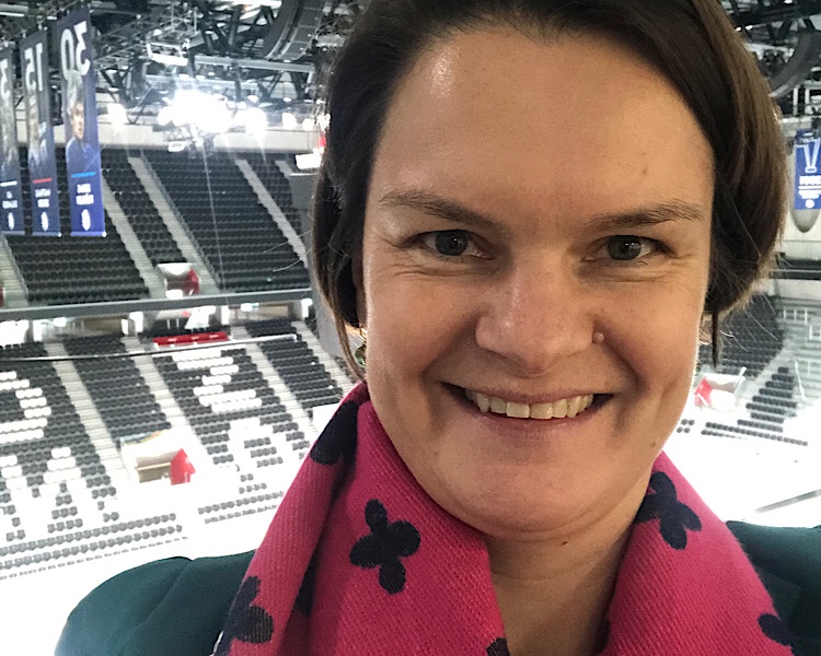 Christine im leeren Eishockeystadion lächelnd mit pinke Schal