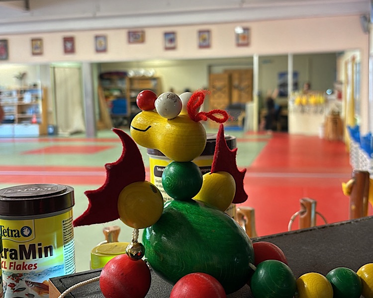 Kleiner Holzdrachen in grün, gelb rot schaut in den Kung-Fu Trainingsraum 