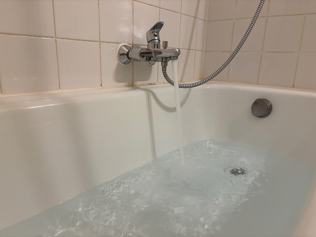 Badewanne halb gefüllt und erläuft Wasser aus dem Hahn rein